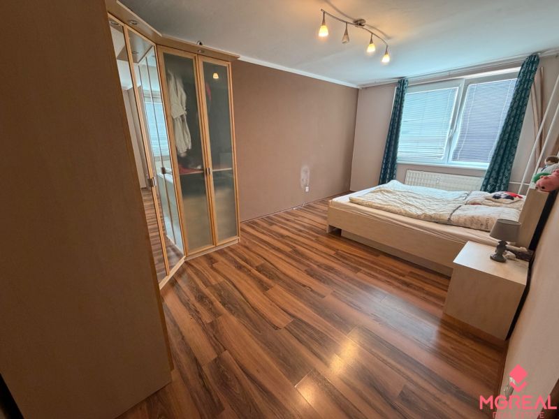 A bedroom in a 3-room apartment with a wood-decor floor and a large built-in wardrobe.