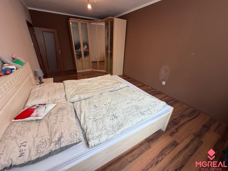 A bedroom with a wood-patterned floor and a built-in wardrobe in a three-room apartment.