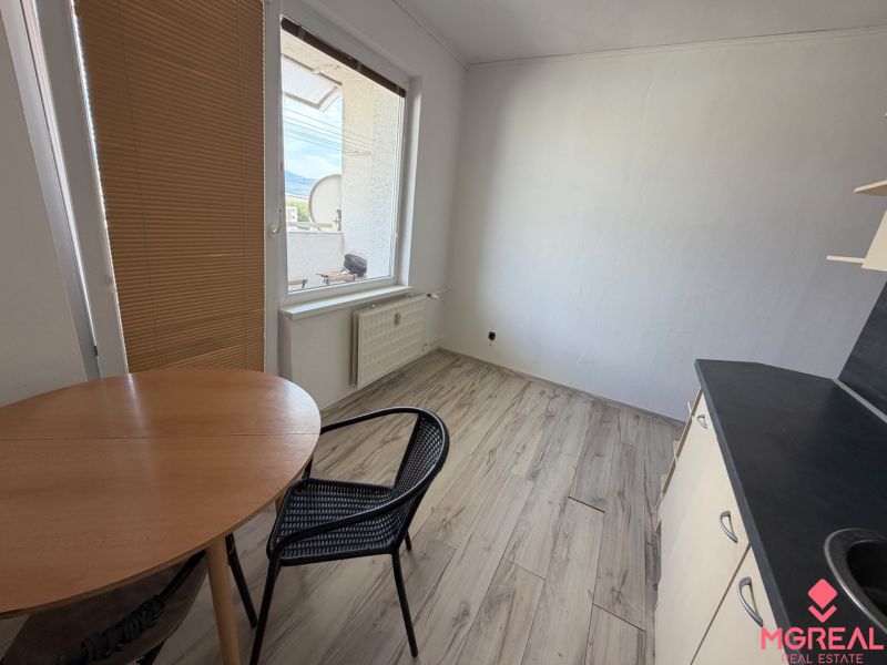A kitchen in a 2-room apartment with a wooden decor floor and a table.