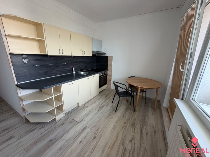 A kitchen in a 2-room apartment with a wooden decor floor and a dining area.