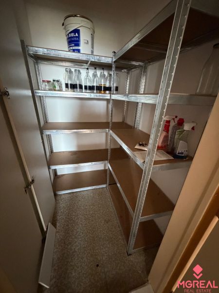 A pantry in a 2-room apartment with a storage rack and plastic bottles.