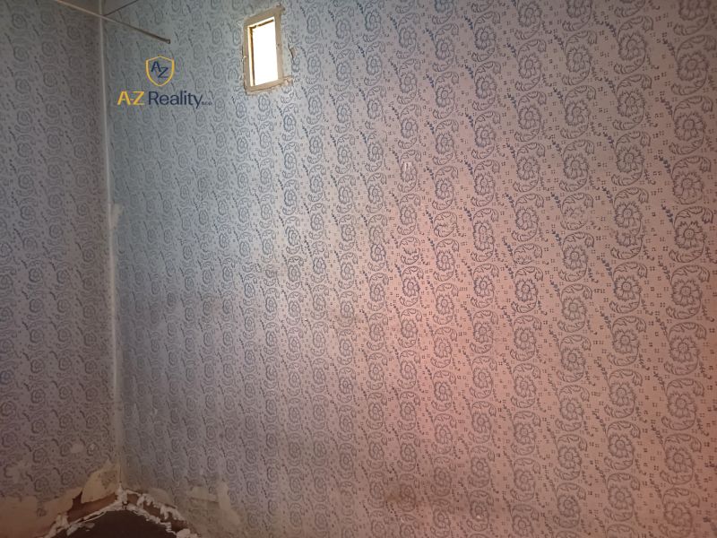 A wall with wallpaper in a family house with a small window.