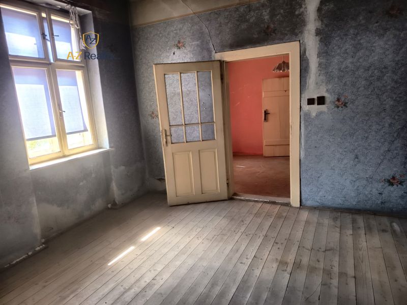 A room with wooden floor decor, blue walls, a bright window, open door.