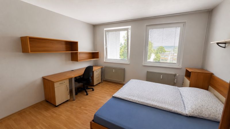 Bedroom in a 3-room apartment with a wooden decor floor and a desk.