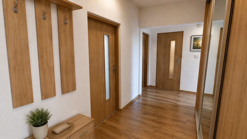 A hallway with a wooden decor floor, a mirror, and wooden furniture in a 3-room apartment.
