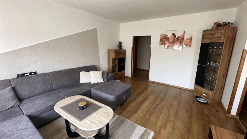 Living room in a three-room apartment with a corner sofa and a wooden decor floor.