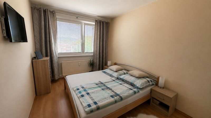 Bedroom with a TV, bed, and wooden decor flooring in a 3-room apartment.