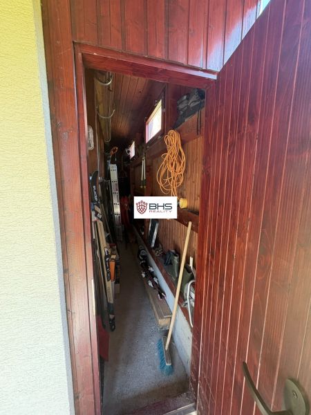 A narrow storage room in a cabin with tools and a small window.