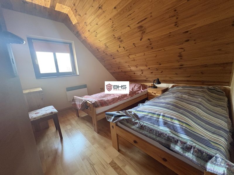 A room in a cottage with a wooden floor decor and two beds under a slanted ceiling.