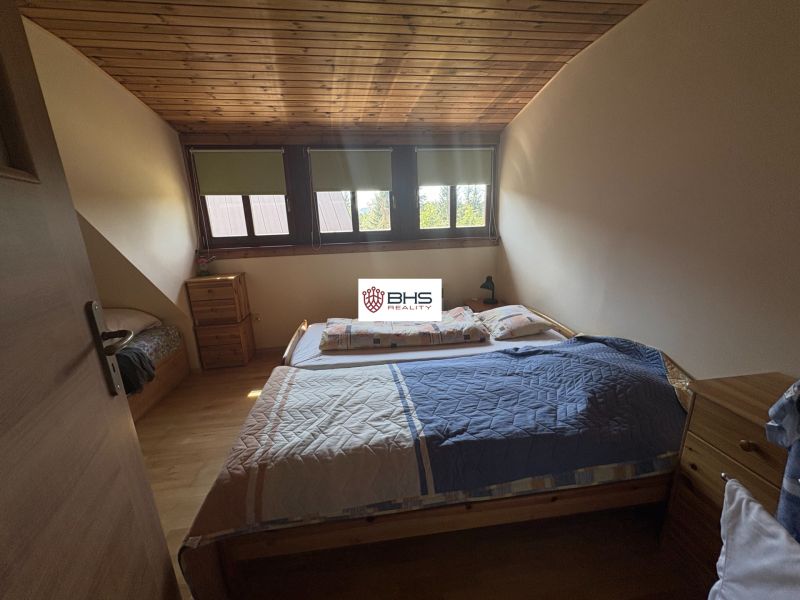 A bedroom with a wooden ceiling and a wood-patterned floor in a cabin.