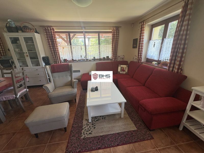 Living room in a cabin with a red sofa, armchair, and dining table.