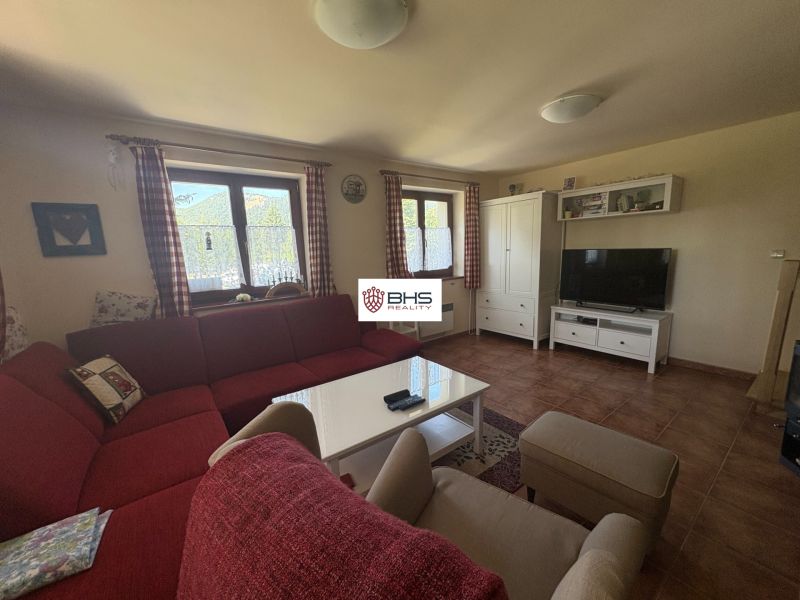 Living room with a red sofa, TV, table, and wooden decor flooring in a cabin.