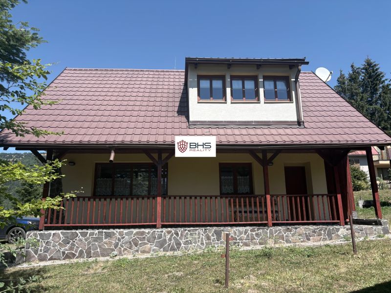 A cottage in Donovaly with a stone base and wooden railing on the porch.