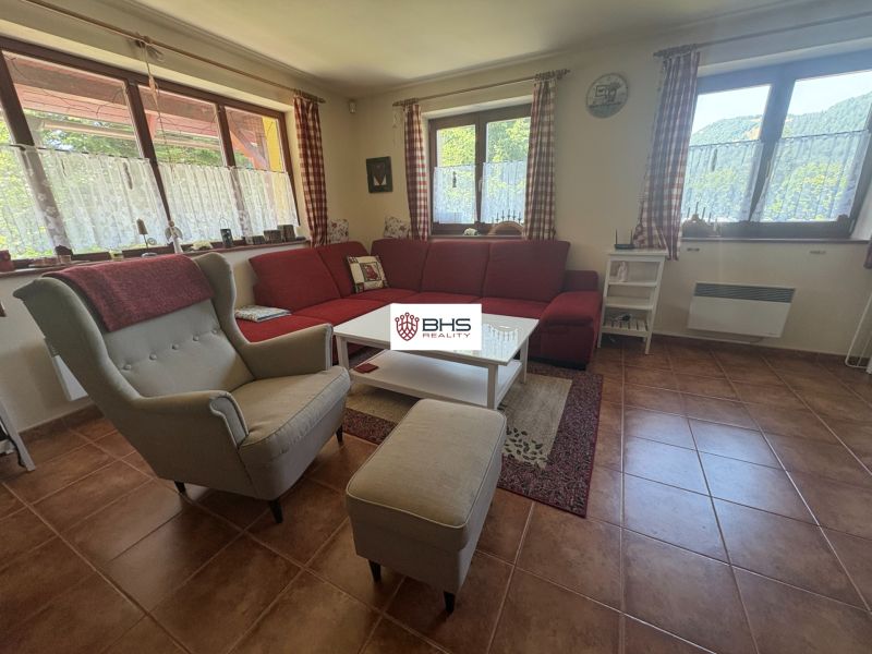 The interior of a cabin with a comfortable armchair, a red sofa, and a floor with a brick appearance.