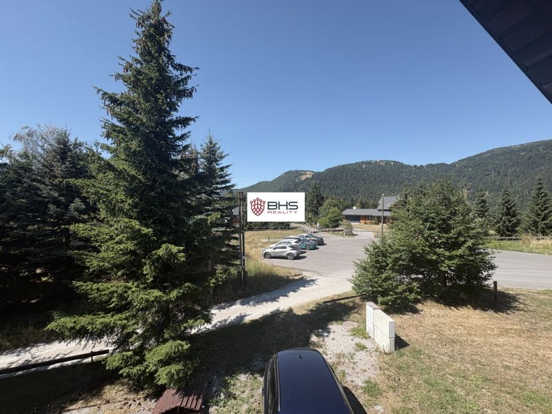 A cottage in Donovaly with a view of the mountains and parking in front of the building.