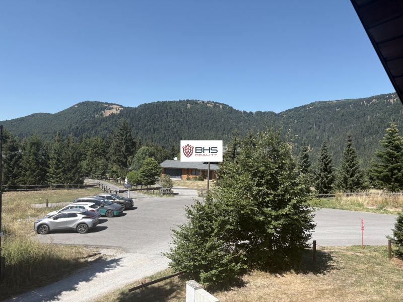 A picturesque view of a cottage in Donovaly surrounded by mountain nature and a parking lot.