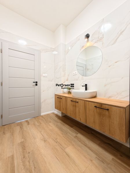 A bathroom with a sink on a wooden decor and a mirror in a 4-room apartment.