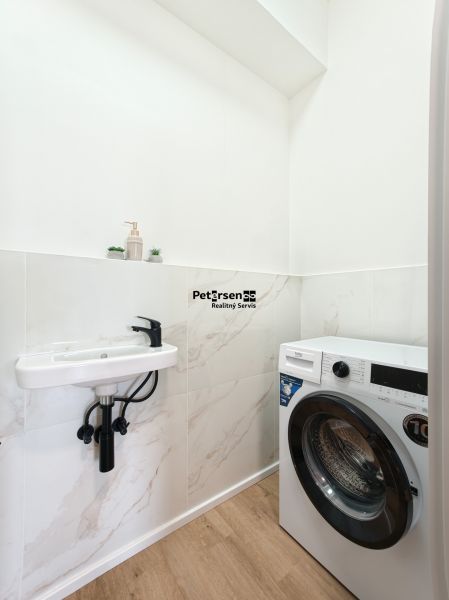 Bathroom with a sink and a washing machine in a 4-room apartment, floor with wood decor.