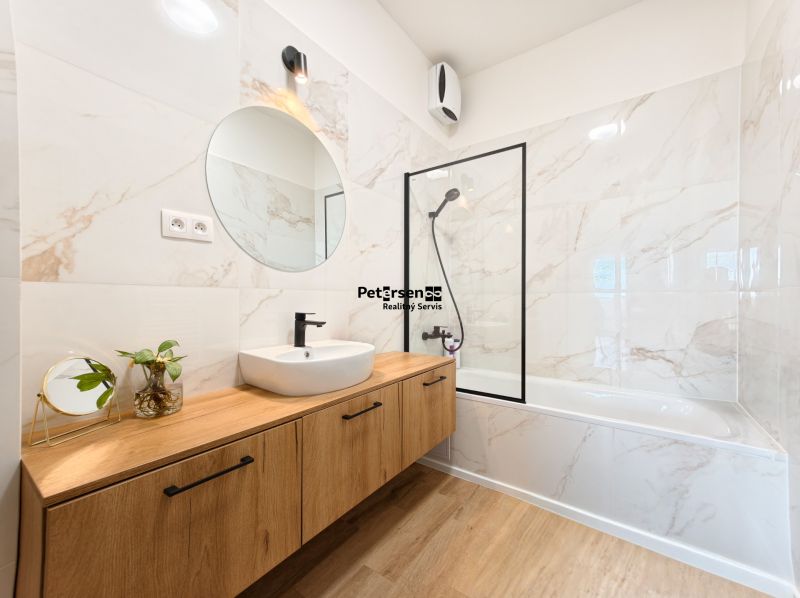 A bathroom in a 4-room apartment with a marble wall and a wooden decor floor.