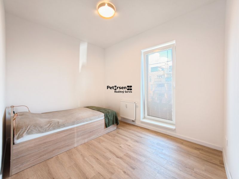 A bedroom in a 4-room apartment with a bed and a wooden decor floor.