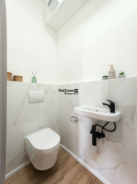 Bathroom with wall-mounted toilet, sink, and floor with wood decor in a 4-room apartment.