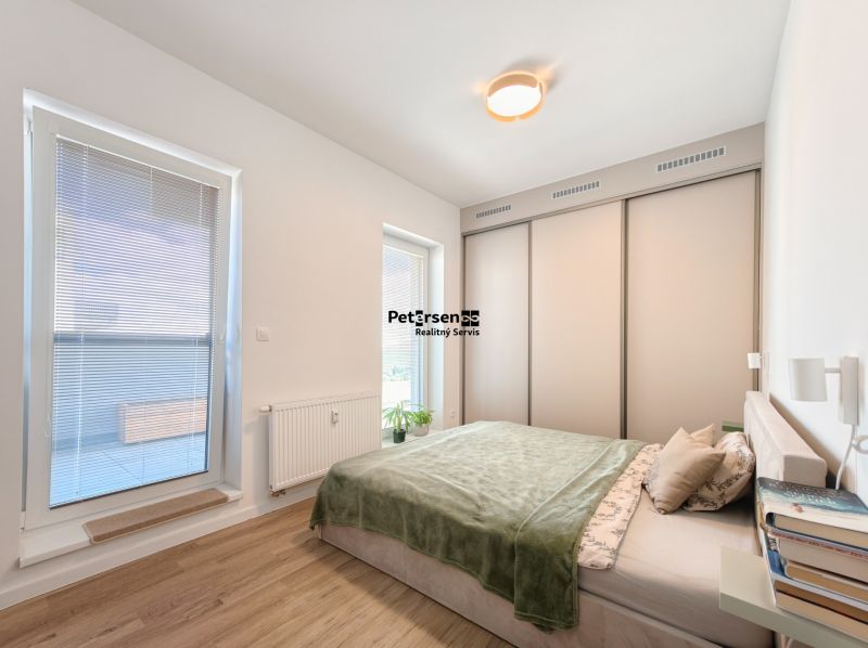 A bedroom with a sofa, built-in wardrobe, and wood-decor flooring in a 4-room apartment.