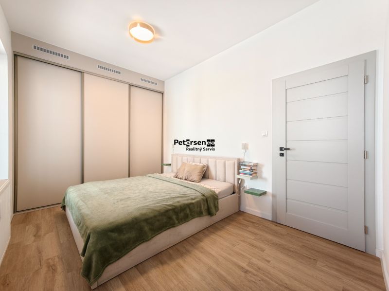 A bedroom with a bed, built-in wardrobe, and wooden decor flooring in a 4-room apartment.