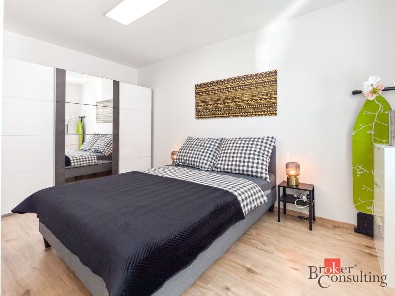 Bedroom with a bed and a mirrored wardrobe in a studio apartment, floor with wood decor.
