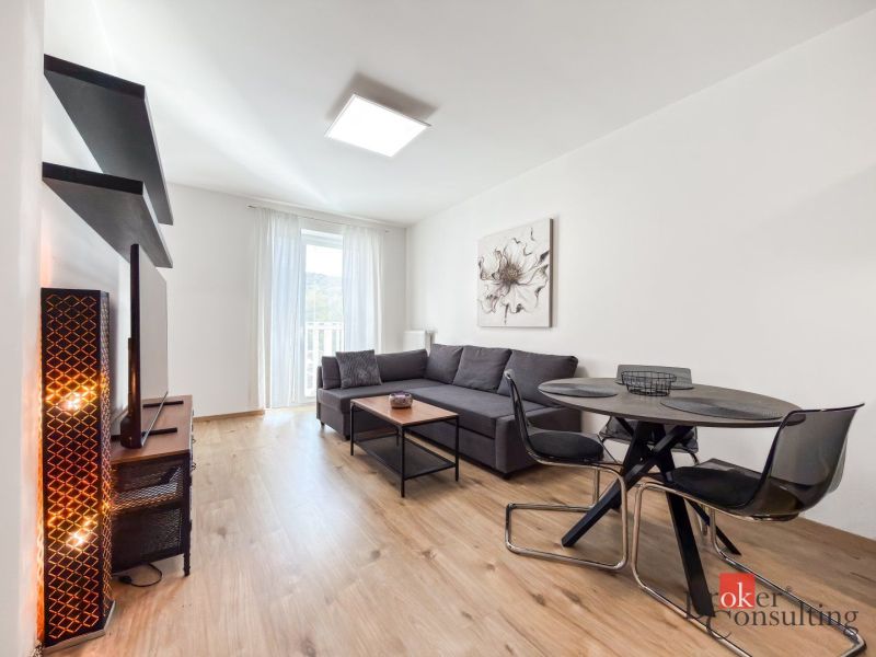 Living room with a dark gray sofa, dining table, and wood-patterned flooring.