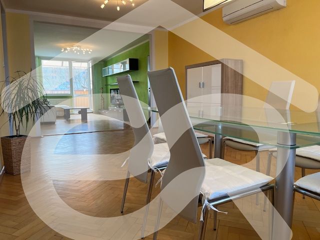 Dining room in a 3-room apartment with a wooden decor floor and a view of the living area.