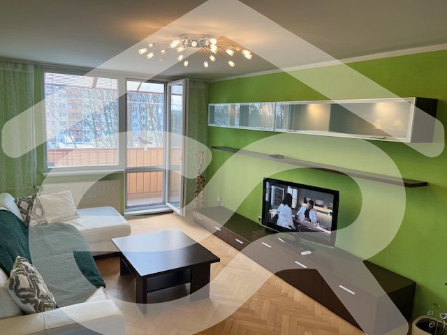 A living room in a 3-room apartment with a wooden decor floor and green walls.