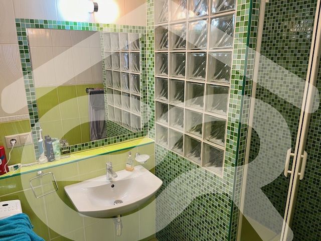 Bathroom in a 3-room apartment with a sink and green mosaic tiles.
