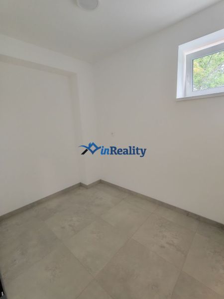 A room in a 3-room apartment with a light floor and a window, without furniture.