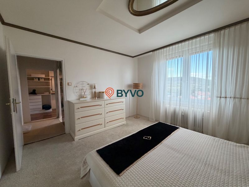Master bedroom in a 4-room apartment with white furniture and a wardrobe in the background.