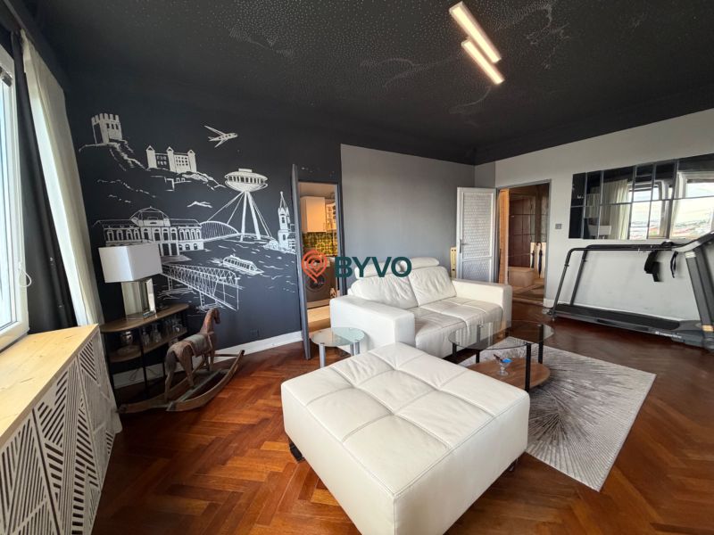 Living room with a sofa, tapestry, treadmill, and wooden decor flooring in a 4-room apartment.
