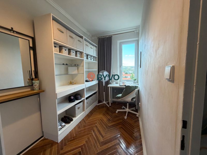 A wardrobe in a 4-room apartment with shelves, a table, and a wooden decor floor.