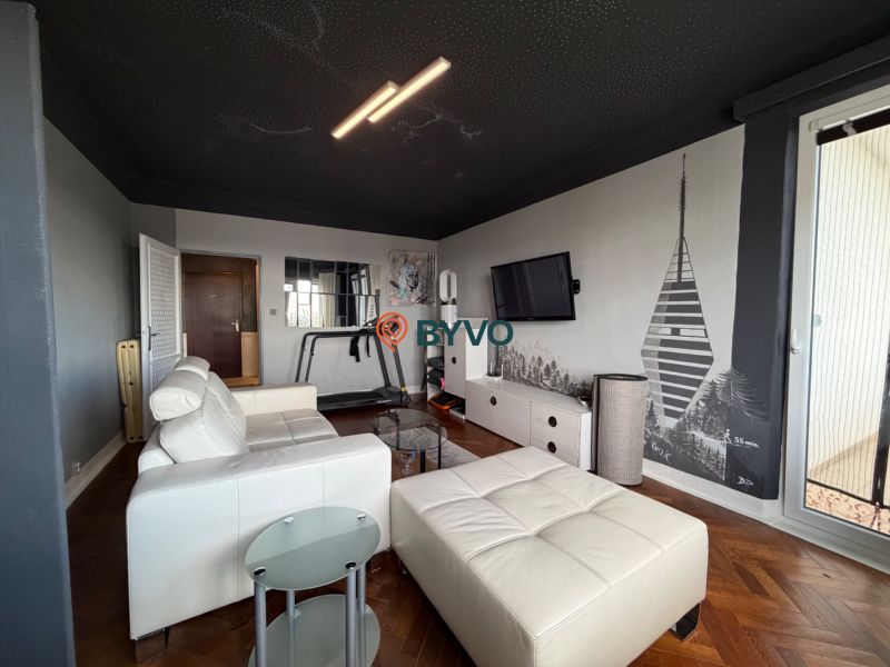 Living room with a white sofa, television, and wood-patterned flooring in a four-room apartment.