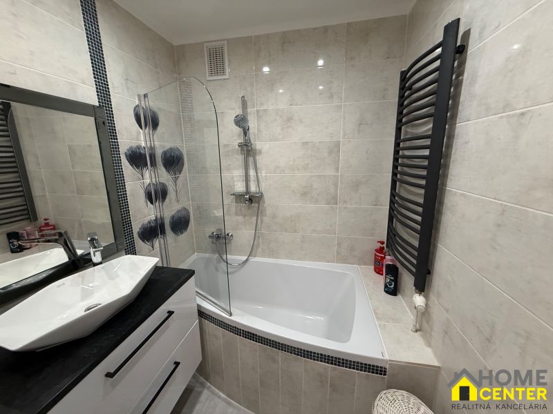 Bathroom with a bathtub, sink, mirror, and ladder radiator in a 3-room apartment.
