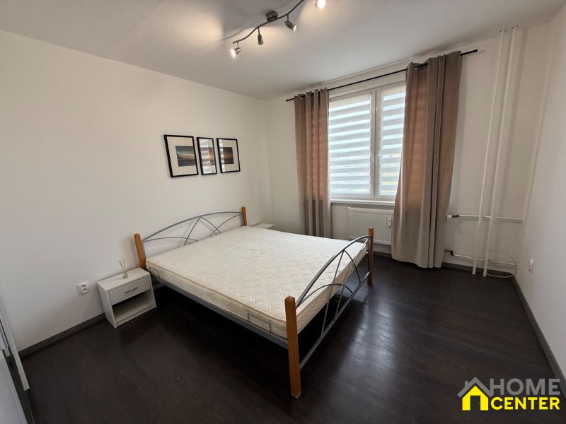 Bedroom in a 3-room apartment with a bed and a window with brown curtains.