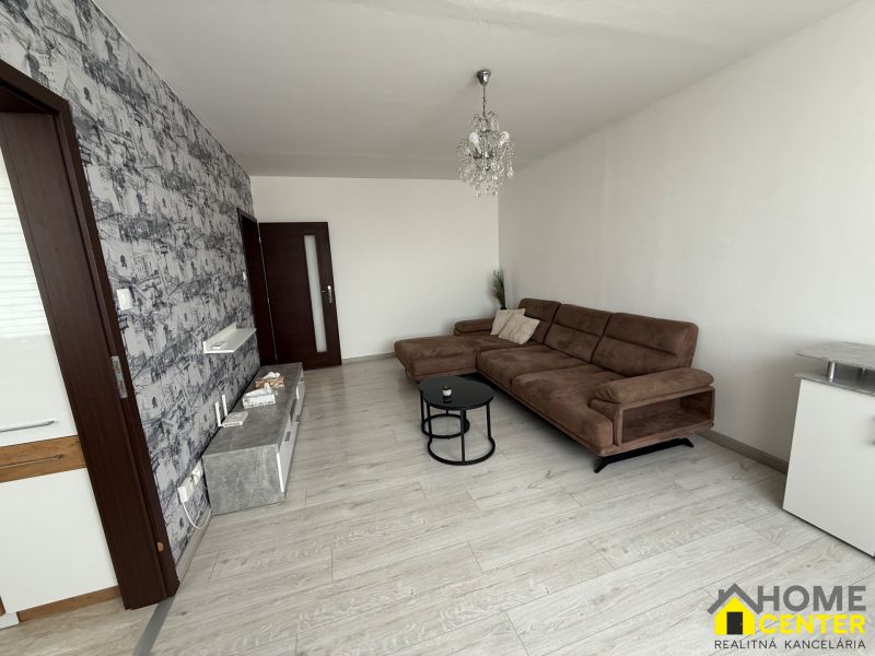 Living room with a brown sofa, wood-patterned flooring, and patterned wallpaper.