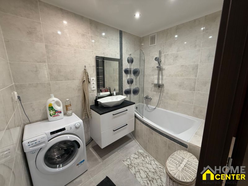 Bathroom with a bathtub, washing machine, and sink in a 3-room apartment.
