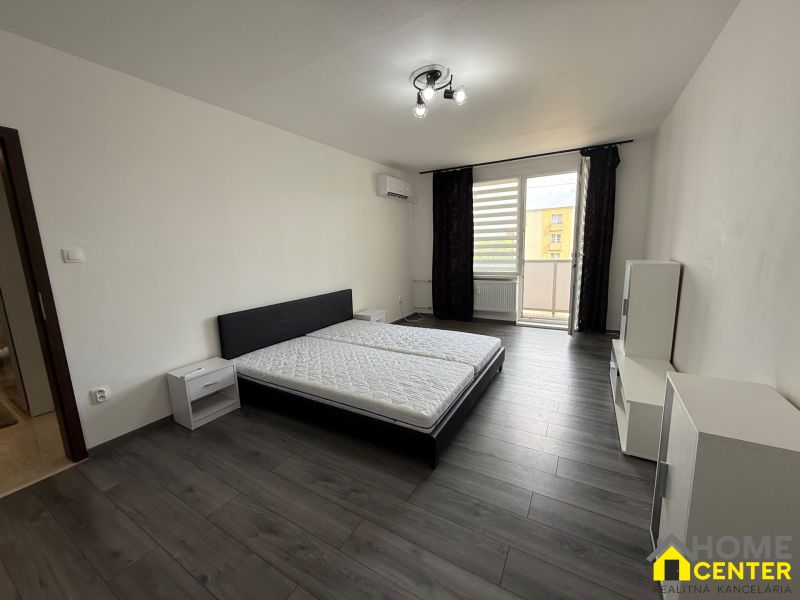 Bedroom in a 3-room apartment with a bed and wooden decor flooring.