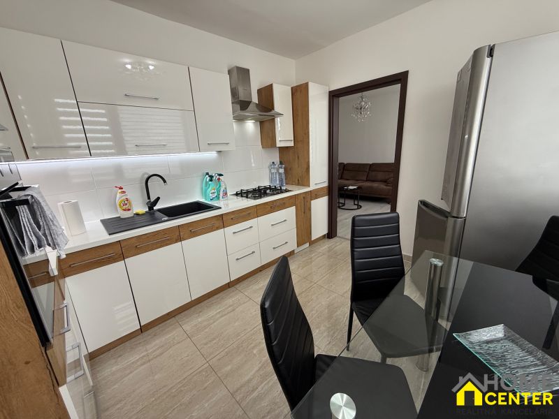 A kitchen with a modern cabinet, black sink, and glass table in a three-room apartment.