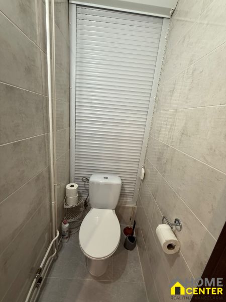 Bathroom with toilet and blinds in a 3-room apartment, beige tiles and accessories.