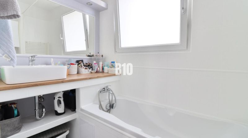 A bathroom in a 3-room apartment with a bathtub, sink, and storage space.
