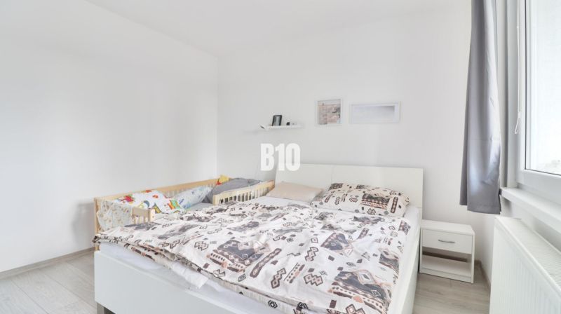 A bright bedroom with a simple bed in a three-room apartment, wooden floor decor.