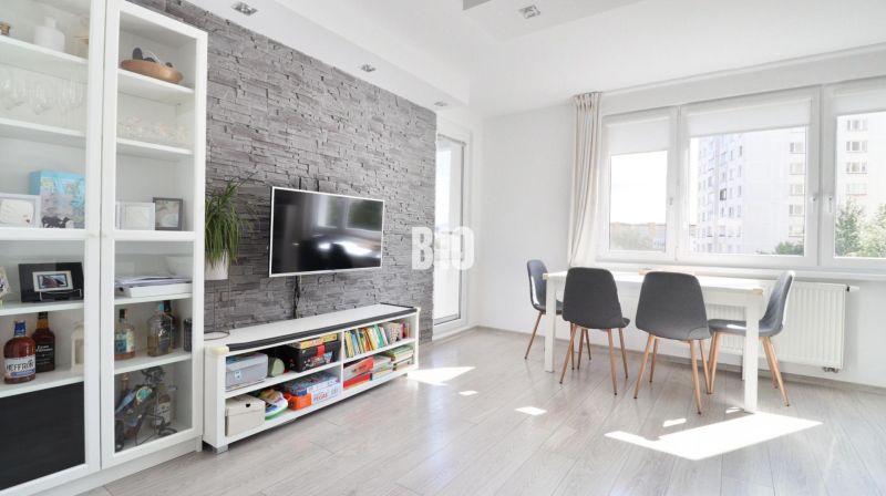 Living room in a 3-room apartment with brick cladding and a wooden decor floor.