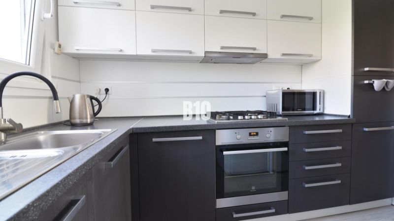A modern kitchen in a 3-room apartment with dark cabinets and silver appliances.