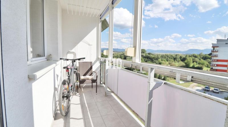 The balcony of a 3-room apartment in Martin with a view of greenery and buildings.