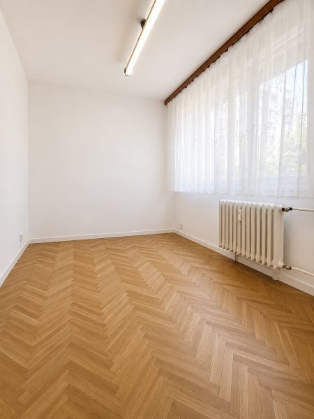 A room in a 3-room apartment with a wooden decor floor and a radiator.
